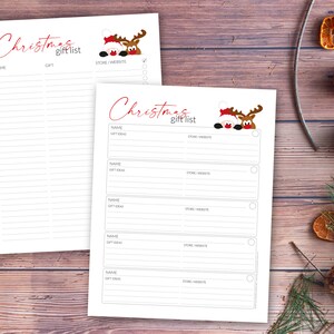 Pu&ograve; includere: Due fogli bianchi di lista regali di Natale con testo rosso e illustrazioni di Babbo Natale e una renna. I fogli hanno sezioni per nome, regalo e negozio/sito web. Su una superficie di legno con pigne e verde.