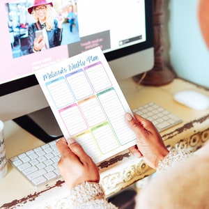 May include: A weekly planner titled "Melissa's Weekly Plan" held in front of a computer screen. The planner has sections for each day of the week, with a space for "Things to Do." The planner's design features pastel colors.