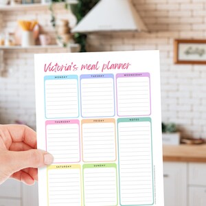 May include: A colorful meal planner titled "Victoria's meal planner" with sections for each day of the week and notes. The planner has a white background with pastel-colored borders around each day's section. The text is in a handwritten style.