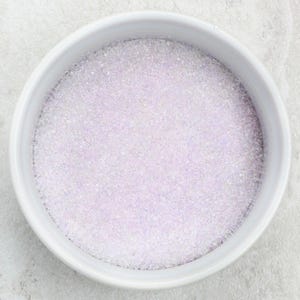 May include: A white bowl filled with iridescent purple sugar crystals.