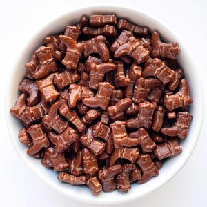 May include: A white bowl filled with brown chocolate boot sprinkles. The sprinkles are in the shape of cowboy boots.