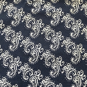 May include: A dark blue fabric with a white repeating pattern of stylized floral designs.