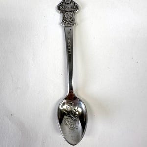 May include: A silver spoon with a crown and the word "ROLEX" on the handle. The spoon is engraved with a tree and the words "GENEVA" and "LUCERNE".