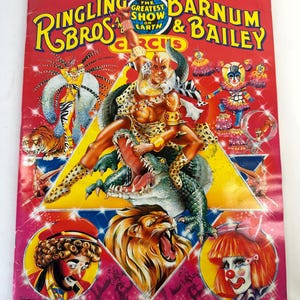 May include: A red, white, and blue program cover for the Ringling Bros. and Barnum & Bailey Circus. The cover features a man in a leopard print costume riding a green alligator. The text on the cover reads "Kenneth Feld Presents The Greatest Show On Earth Ringling Bros. and Barnum & Bailey Circus".