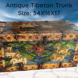 Op de afbeelding: Antieke Tibetaanse kist met ingewikkelde handgeschilderde details. De kist heeft een kleurrijk tafereel met tijgers, mythische wezens en bergen. De kist is gemaakt van hout en heeft metalen accenten. Afmeting: 34x16x17 inch.