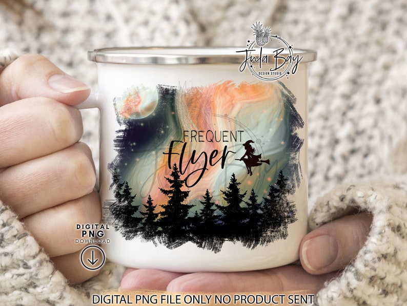 May include: A white enamel mug featuring a graphic print of a silhouette of a witch on a broomstick flying over a dark forest. The design includes a swirling orange and blue sky background with the text Frequent Flyer printed in black script.