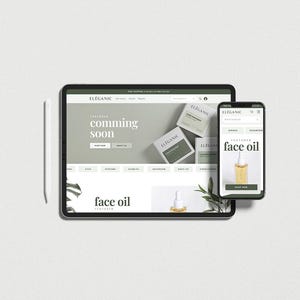 May include: A tablet and smartphone display a website with the text "coming soon" and "face oil." The website features a minimalist design with green and white elements. A stylus and a sprig of greenery are also present.