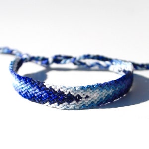 May include: A blue and white friendship bracelet with a woven pattern.