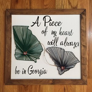 May include: A piece of my heart will always be in Georgia. This string art features the outlines of Georgia and South Carolina, with a red heart in each state. The states are connected by a string.