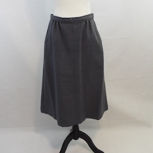 May include: A dark gray midi skirt with a straight silhouette and a waistband with a slight elastic.