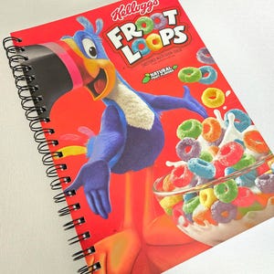 May include: A spiral-bound notebook featuring a bright red cover with the Kellogg's Froot Loops logo, the Toucan Sam character, and a bowl of colorful cereal loops in milk. The text reads Kellogg's Froot Loops and Natural Fruit Flavors.