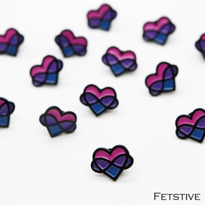 May include: Multiple bi pride pins with an infinity symbol inside a heart. The pins are black, pink, blue, and purple.