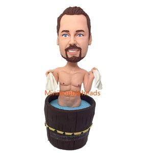 Peut inclure: Une figurine de tête de culbuteur personnalisée représentant un homme barbu tenant une serviette et assis dans un tonneau en bois rempli d'eau bleue. La figurine est étiquetée "Boyfriend Bobbleheads".