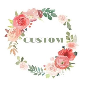 May include: Watercolor floral wreath with the word "CUSTOM" in green block letters. The wreath features pink, peach, and red roses, with green leaves and accents, arranged in a circular design on a white background.