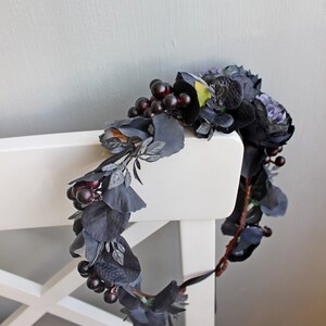May include: A dark blue and black floral crown with berries. The crown is made of artificial flowers and berries.