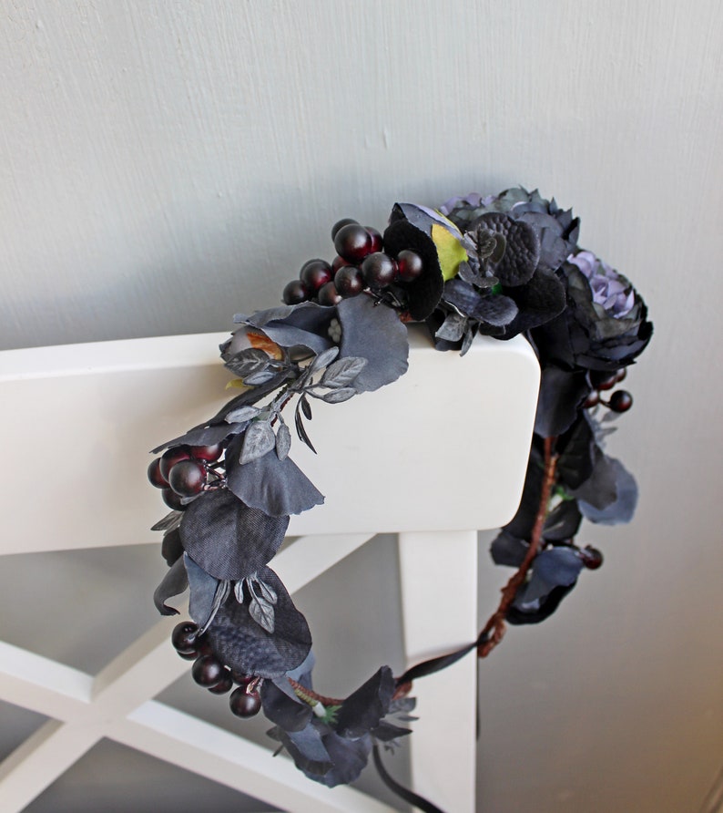 May include: A dark blue and black floral crown with berries. The crown is made of artificial flowers and berries.