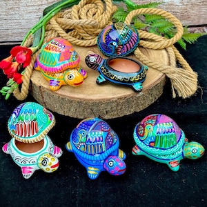 May include: Five hand-painted turtle shaped trinket boxes. The turtles are painted in bright colors with intricate designs. The boxes are open to reveal the inside.