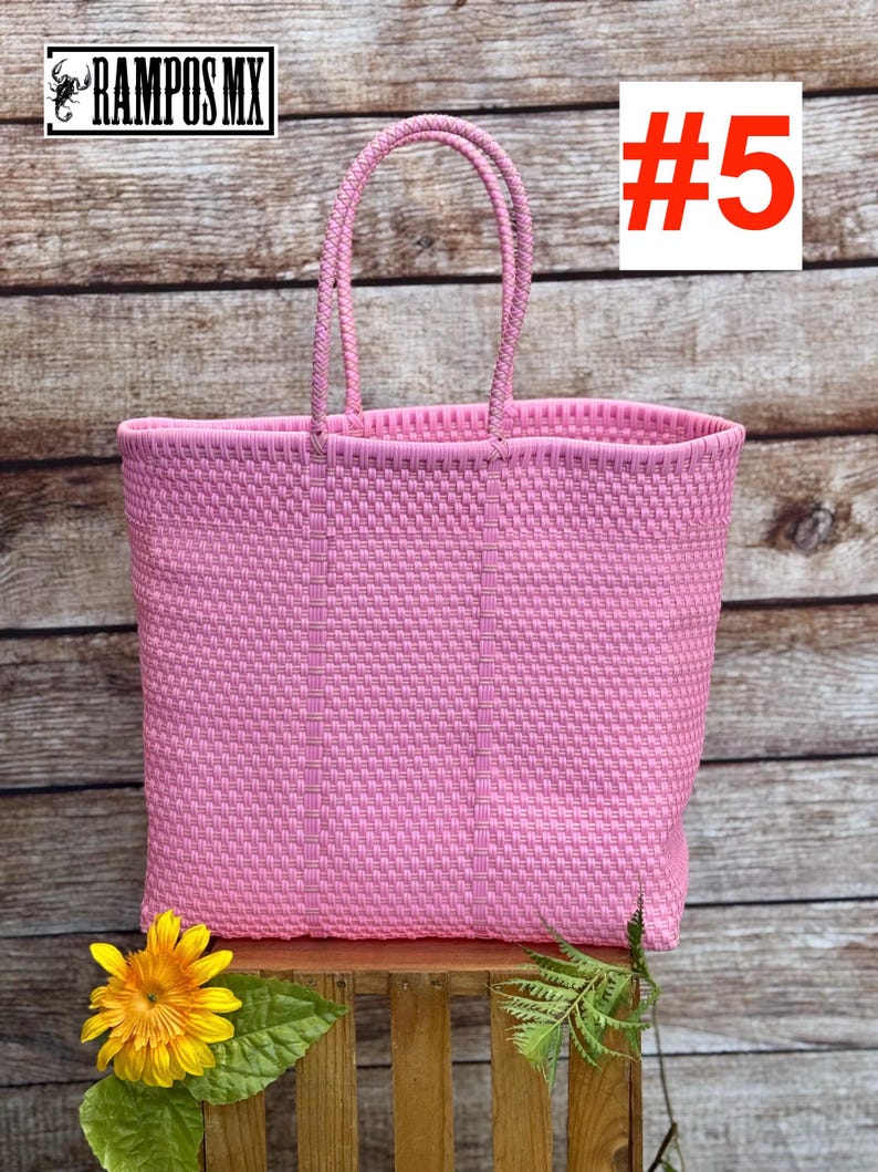 May include: A pink woven tote bag with two handles. The bag is rectangular and has a textured pattern. The number 5 is displayed in a white box with a red outline. The brand name "RAMPOS MX" is in the upper left corner.