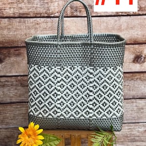 May include: A gray and white woven tote bag with a geometric pattern. The bag has a rectangular shape with a handle. The text "#11" is in the upper right corner. The brand name "RAMPOS MX" is in the upper left corner.