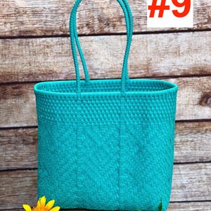 May include: A bright turquoise woven tote bag featuring a structured rectangular body and two matching arched handles. The bag displays a consistent basket-weave pattern throughout its surface. The text RAMPOS MX and the number #9 are visible.