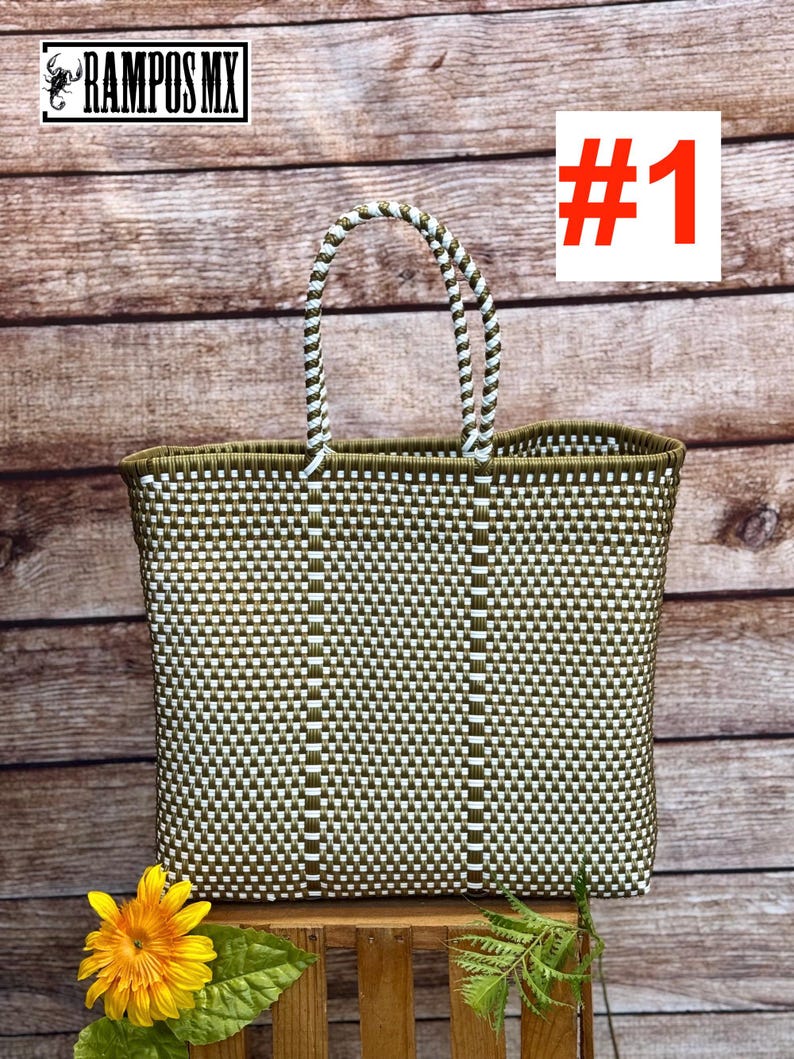 May include: A woven tote bag with a green and white checkered pattern. The bag has a rectangular shape with a sturdy handle. The handle is white and green. The bag is sitting on a wooden surface. The text "#1" is in the upper right corner.