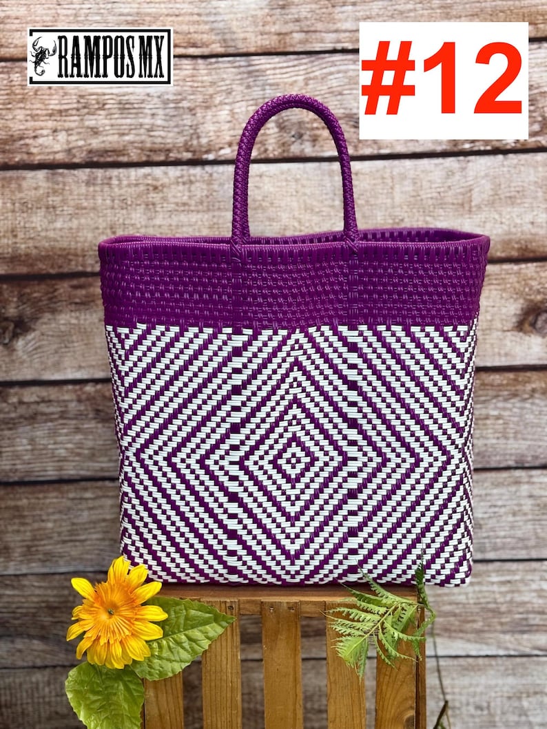 May include: A woven tote bag with a geometric diamond pattern in white and purple. The bag has a solid purple top and handle. The number 12 is displayed in red on a white background. The bag is sitting on a wooden surface.