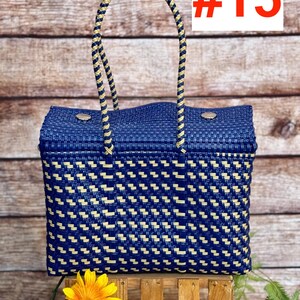 Op de afbeelding: Een rechthoekige gevlochten tas met een geometrisch patroon in donkerblauw en cr&egrave;me. De tas heeft twee gevlochten hengsels in bijpassende kleuren en twee zilverkleurige metalen drukknopen aan de bovenrand. De tekst #15 is zichtbaar.
