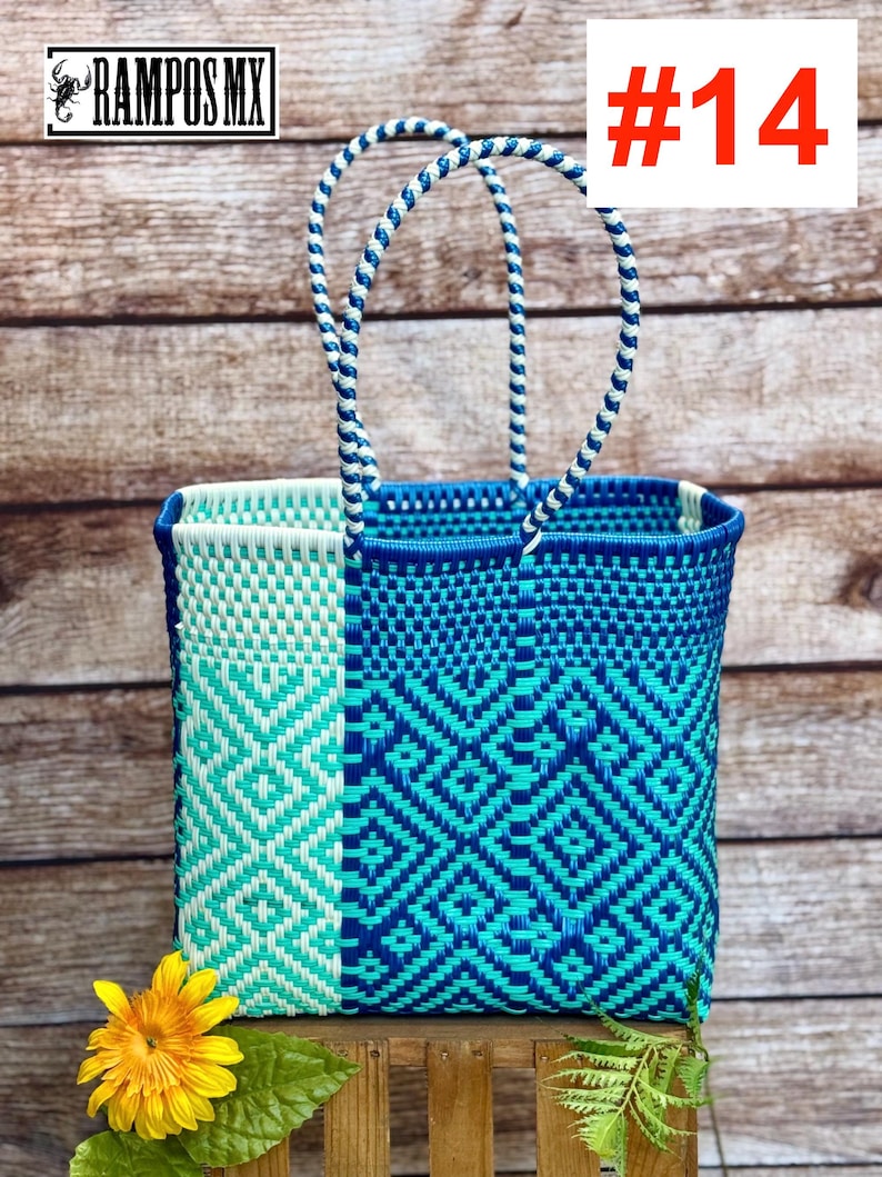 May include: A rectangular woven tote bag featuring a geometric diamond pattern in shades of light blue, turquoise, and dark blue. The bag has two braided handles in a matching blue and white color scheme and a structured open top design.