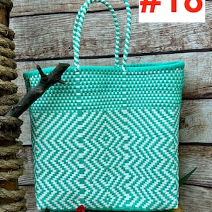 May include: A woven tote bag in turquoise and white, featuring a geometric diamond pattern. The bag has two handles and a rectangular shape. The text "#18" is in the upper right corner. The bag is made of a durable, woven material.