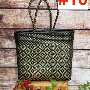 May include: A black and gold woven tote bag featuring a geometric diamond pattern, two braided handles, and the text RAMPOS MX and #16. The bag is constructed from thin plastic strips woven in a tight, repeating grid design with a rectangular shape.