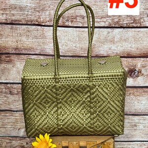 Op de afbeelding: Een geweven tas in metallic olijfgroen met twee touw-handvatten en twee zilverkleurige metalen drukknopen aan de bovenrand. De tas heeft een herhalend geometrisch ruitpatroon. De tekst RAMPOS MX en #3 zijn zichtbaar op de afbeelding.