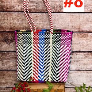 May include: A rectangular tote bag woven from plastic strips in a multi-colored chevron pattern featuring red, blue, green, black, white, and magenta. The bag has two red and white twisted rope handles and displays the text RAMPOS MX and #8.