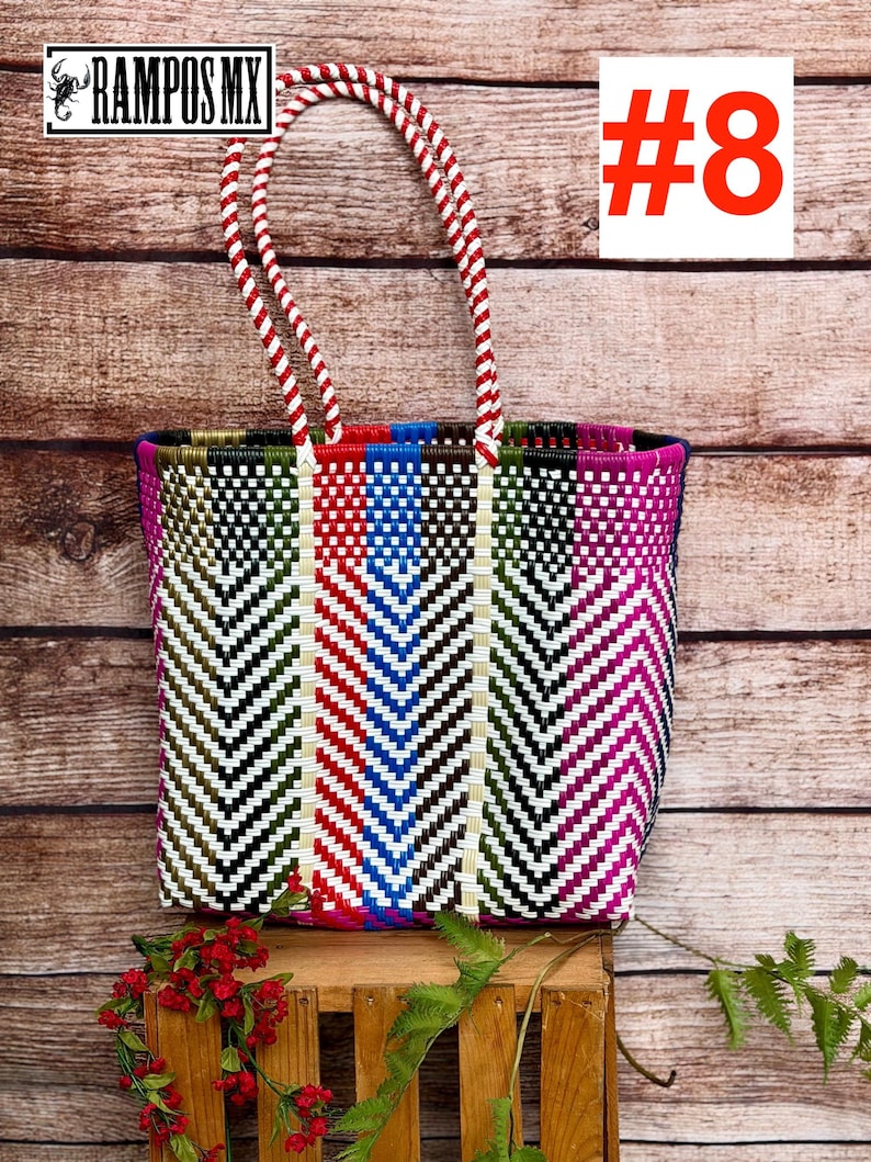 May include: A rectangular tote bag woven from plastic strips in a multi-colored chevron pattern featuring red, blue, green, black, white, and magenta. The bag has two red and white twisted rope handles and displays the text RAMPOS MX and #8.