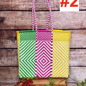 May include: A rectangular tote bag featuring a woven plastic pattern in bright green, hot pink, and yellow with white accents. The bag has two matching braided handles in pink and white. The text RAMPOS MX and a scorpion icon appear in the corner.