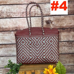 Op de afbeelding: Een rechthoekige gevlochten tas met een geometrisch ruitpatroon in donkerrood en metallic zilver. De tas heeft twee bijpassende gevlochten handvatten en een gestructureerd deksel. De tekst RAMPOS MX en een schorpioen-icoon zijn zichtbaar.