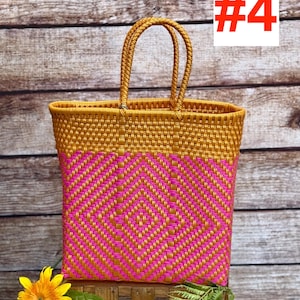 May include: A woven tote bag featuring a gold and hot pink geometric diamond pattern. The bag has two matching gold braided handles and a rectangular structure. The top portion is solid gold, while the lower section displays the diamond design.