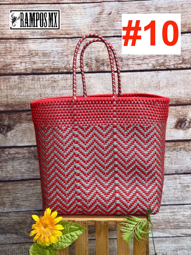 May include: Red and silver woven tote bag with a chevron pattern. The bag has two handles and the text "#10" in red. A yellow flower and green leaves are in the foreground. The brand name "RAMPOS MX" is in the top left corner.