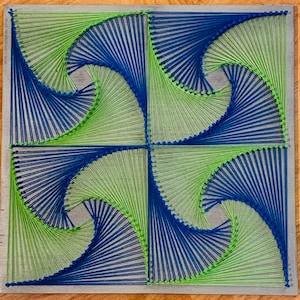 May include: A square piece of string art with a geometric design. The design is made up of blue and green string, creating a swirling pattern.