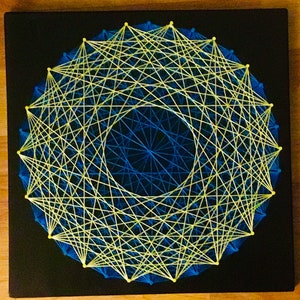 May include: A circular string art piece with a yellow string design on a black background. The string art design creates a geometric pattern with a blue circle in the center.