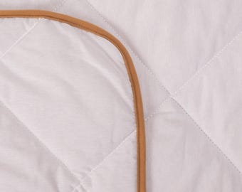 Könnte beinhalten: Ein weißer gesteppter Betttopper mit braunem Rand.