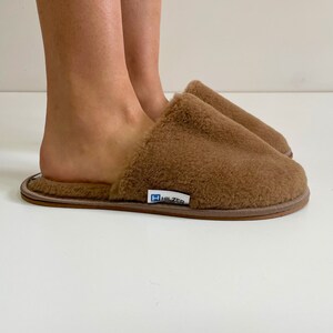 May include: A pair of brown fuzzy slippers with a Hilzer logo on the sole.