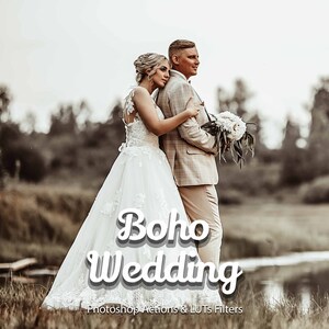 Könnte beinhalten: Ein Brautpaar posiert für ein Hochzeitsfoto auf einem Feld. Die Braut trägt ein weißes Hochzeitskleid und der Bräutigam trägt einen beigen Anzug. Das Paar steht in der Nähe eines Gewässers und im Hintergrund sind Bäume zu sehen. Der Text "Boho Wedding" ist über das Bild gelegt.