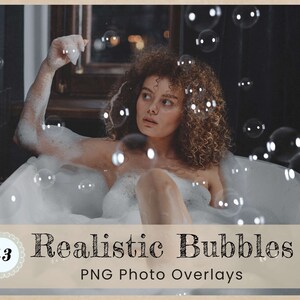 May include: A woman relaxes in a bathtub filled with bubbles. The bubbles are floating in the air and on the surface of the water. The woman has curly brown hair and is wearing a white bathing suit. The background is a dark bathroom with a mirror and a tiled wall.