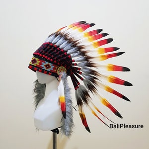 Może przedstawiać: Indian headdress z czarną, koralikową koroną i kolorowymi piórami w kolorze czerwonym, żółtym i białym. Headdress ma ozdobny koralikowy pasek i futrzane wykończenie. Tekst "BaliPleasure" jest widoczny po prawej stronie.