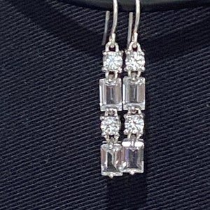 May include: A pair of silver dangle earrings with clear rectangular and round cubic zirconia stones.