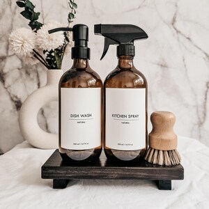 Pu&ograve; includere: Due bottiglie di vetro ambrato con etichetta "Dish Wash" e "Kitchen Spray" con pompe nere e ugello spray. Sono presenti anche una spazzola di legno e un vassoio di legno scuro. Le bottiglie sono da 500 ml.