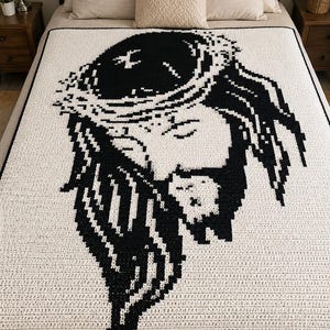 May include: A rectangular crochet blanket featuring a high-contrast black and white pixelated graphic of a face wearing a crown of thorns. The design is centered on a cream-colored background with a thin black border framing the entire piece.