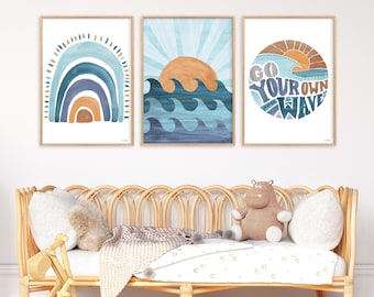 May include: Three framed prints with a beach theme. The first print features a blue and orange rainbow. The second print features a blue ocean with waves and a setting sun. The third print features a circle with the text "Go Your Own Wave" and a blue ocean with a setting sun.