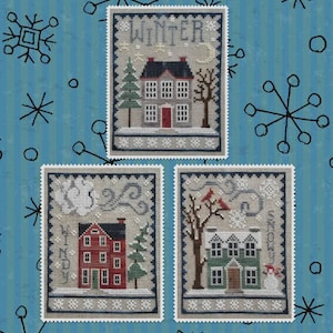 May include: Three cross-stitch designs featuring winter scenes. Each design depicts a house, a tree, and the word "WINTER", "WINDY", or "SNOW". The background is a light blue with snowflakes.