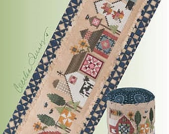 May include: A needlepoint design featuring a tiny town scene with houses, trees, and geometric patterns. The design is framed with a blue and white border. The text "QUILTED tiny town" is visible. The Heart in Hand needleart logo is in the upper left corner.